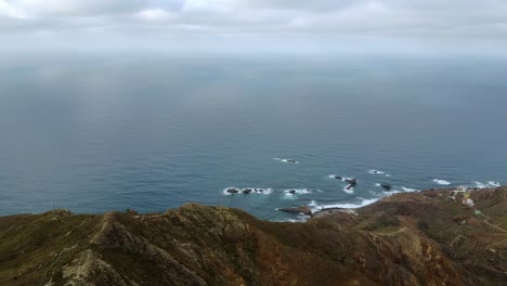 Open-clear-blue-sky,Aerial-overview-above-the-mountainous-coastline,-small-houses-stretching-along-the-coast,-high-pointe