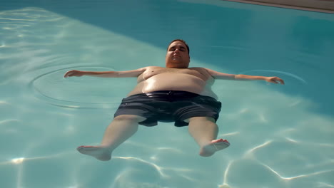 overweight man peacefully floating on his back in a swimming pool