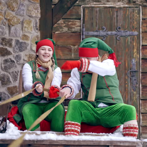 christmas elves ride wooden sledges. new year is coming. christmas eve. boy and girl wear christmas clothes. having fun.
