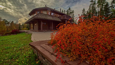 timelapse shot of dried red leaves on a warm autumn day in rural countryside with view of beautiful cottage in the background