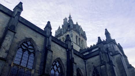 Slow-moving-clouds-moving-above-a-church-and-statue,-on-a-cold-and-cloudy-day-in-Scotland