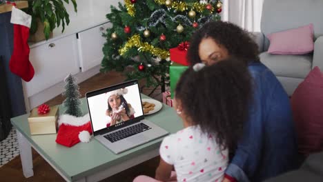 Happy-african-american-mother-and-daughter-on-video-call-on-laptop-with-female-friend-at-christmas