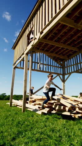 kids playing and balancing on an unfinished wooden structure