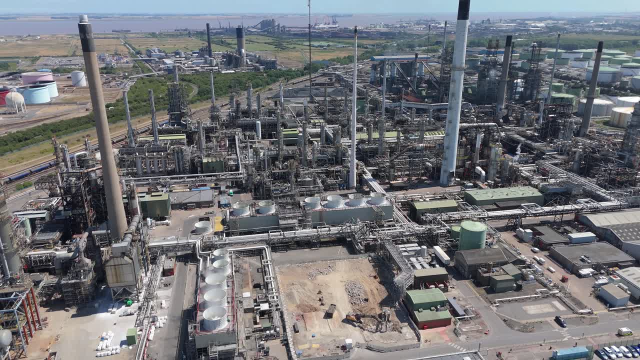 Ampio filmato aereo con drone che mostra un grande impianto chimico, silos di carburante industriali, fumo di scarico e torce di gas vicino a Immingham, Inghilterra, Regno Unito