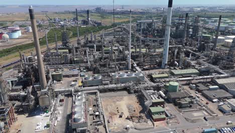wide aerial drone footage showing heavy chemical plant, industrial fuel silos, exhaust smoke and gas flares near immingham england uk