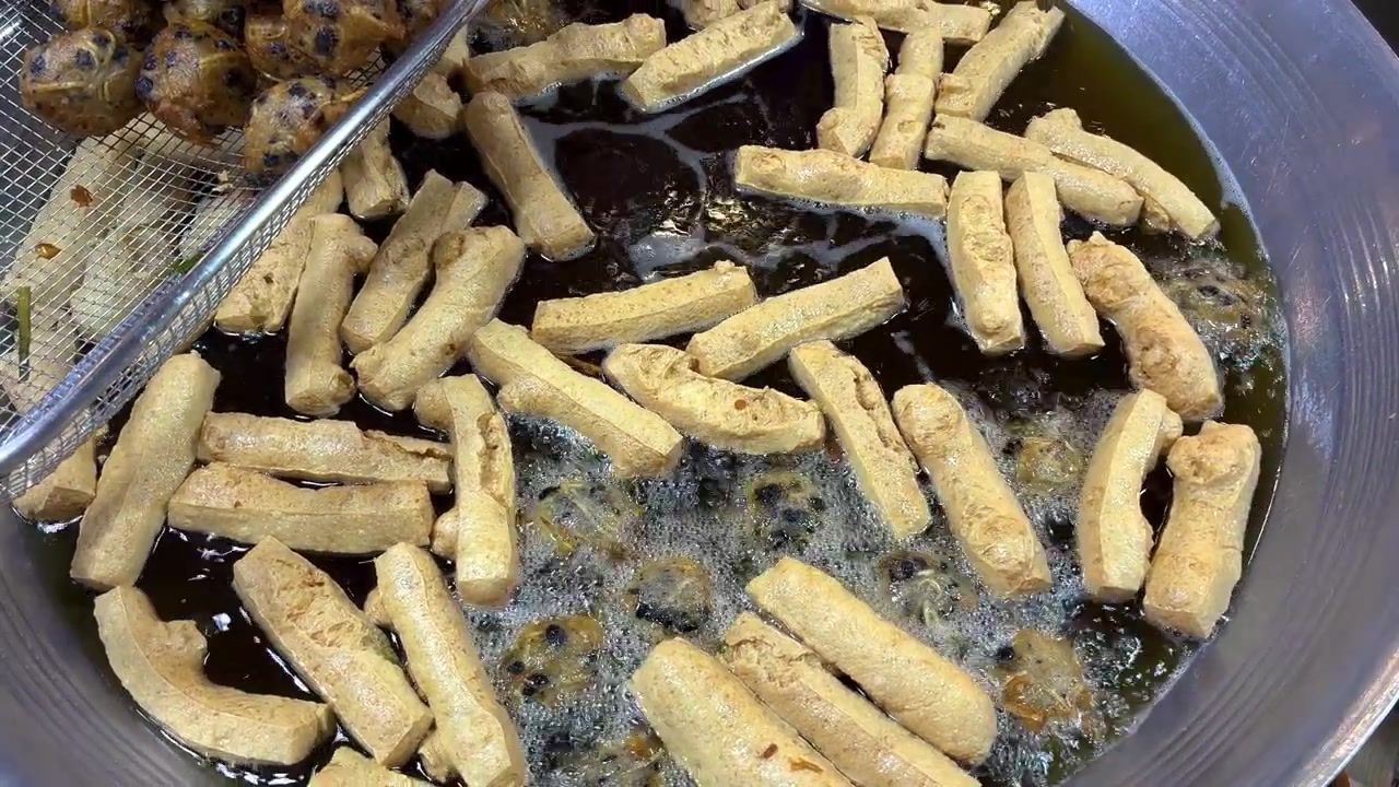 Una ripresa ravvicinata dall'alto che cattura il vivace processo di cottura degli snack di street food thailandese.
