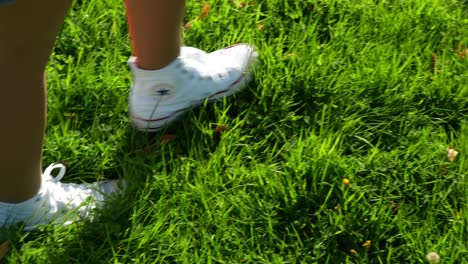 Close-up-of-female-legs-walking-on-a-green-grassy-field,-sunny-summer-day,-in-4K,-Slow-Motion