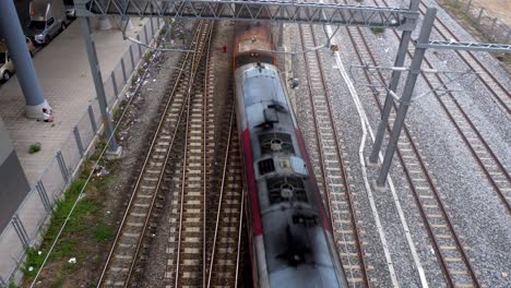 view from the top of a cargo train moving from the top to the bottom of the frame, passing by bang sue train station in bangkok, thailand