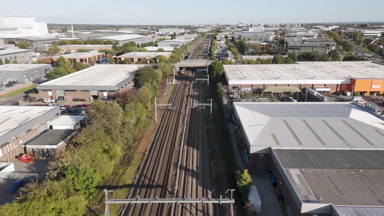 Aerial view of a Southwestern Railway train passing through the Slough industrial estate, surrounded by warehouses and factories, October 2024