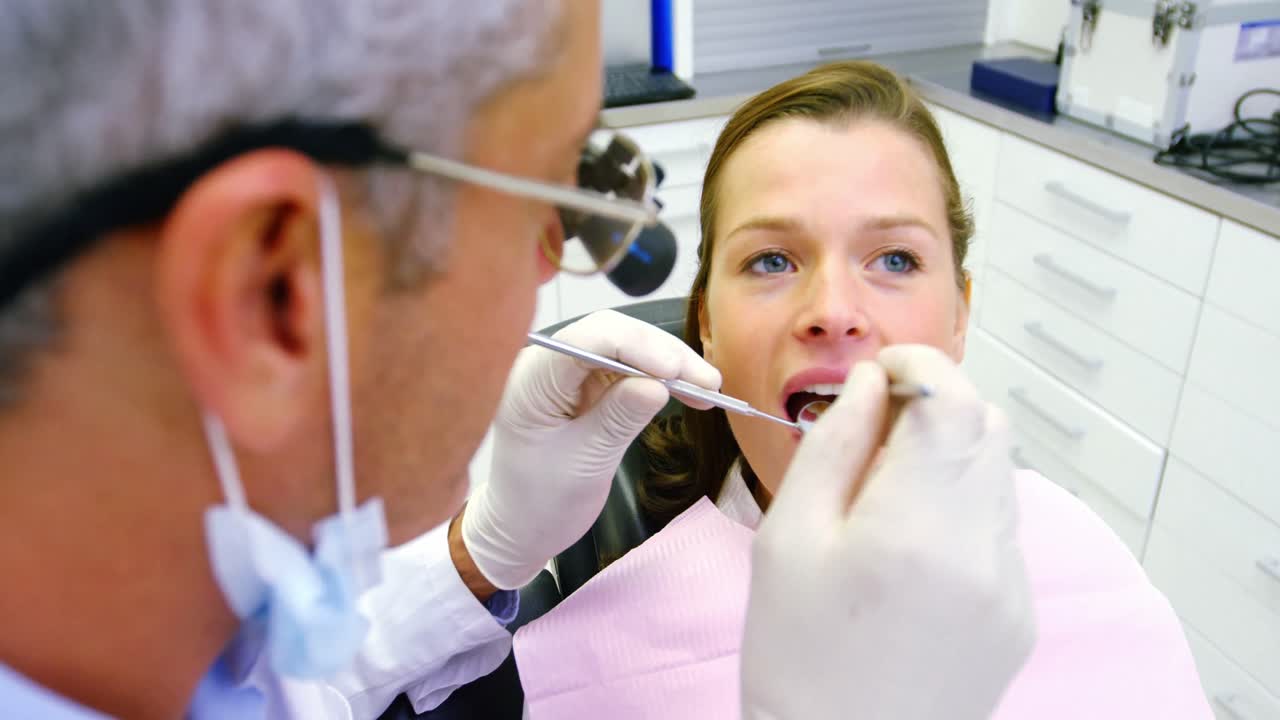 dentista examinando a una paciente femenina con herramientas