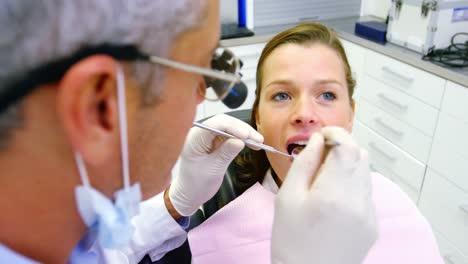 Dentist-examining-a-female-patient-with-tools