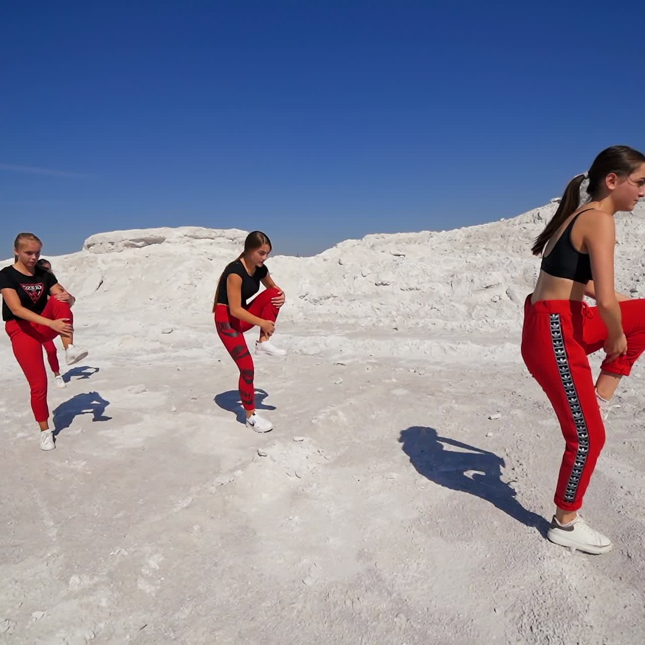 Group of girls dancing on the rocky landscape on sunny day. Female Caucasian collective performing hip hop acrobatic dance