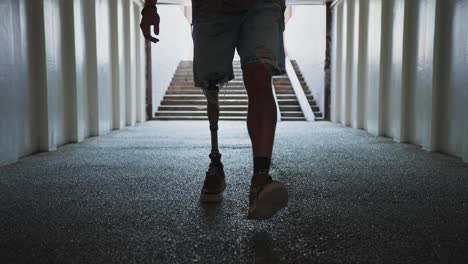 person with a prosthetic leg walking through an underground passage