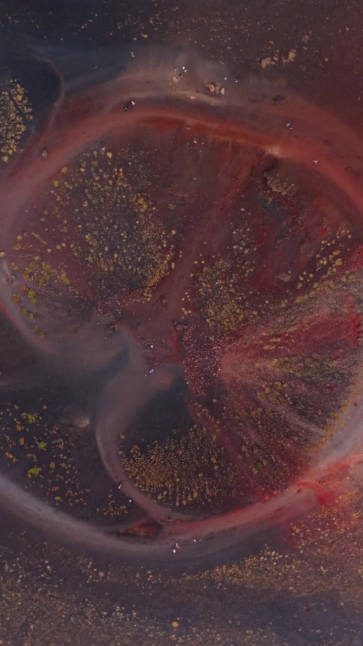 Etna's volcanic crater forms an abstract circle as drone spins overhead.