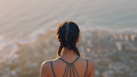 woman on mountain top looking at view of ocean at sunset girl standing on edge of cliff enjoying travel freedom