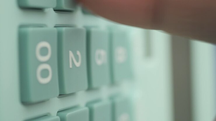 A close-up of a finger pressing buttons on a calculator keypad