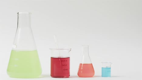 Coloured-liquids-in-flasks-on-white-background-with-copy-space,-slow-motion