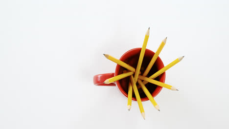 Lápices-De-Color-Amarillo-Guardados-En-Una-Taza-Roja-Sobre-Fondo-Blanco.