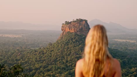 a woman admires the majestic sigiriya rock as the sun rises over the sri lankan jungle. a peaceful and iconic moment in nature, perfect for travel and cultural themes.