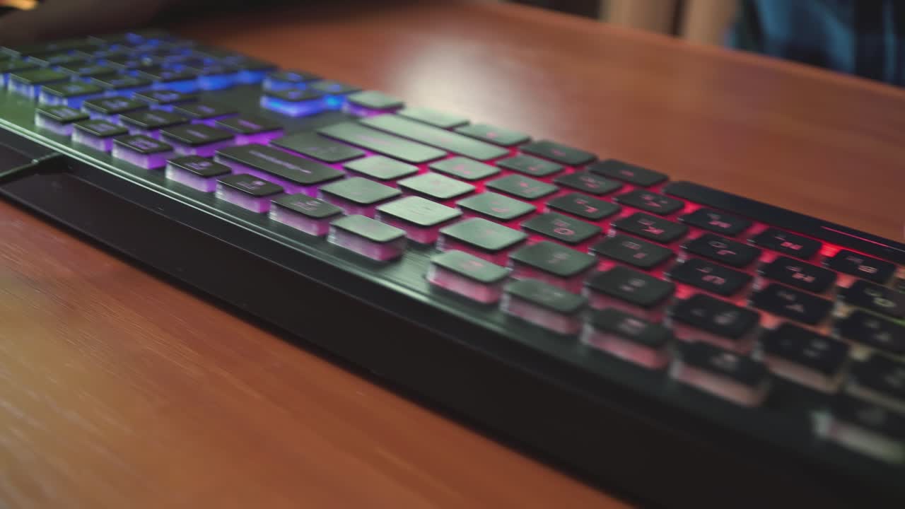 joven jugador juega un videojuego utiliza el teclado iluminado del juego 03