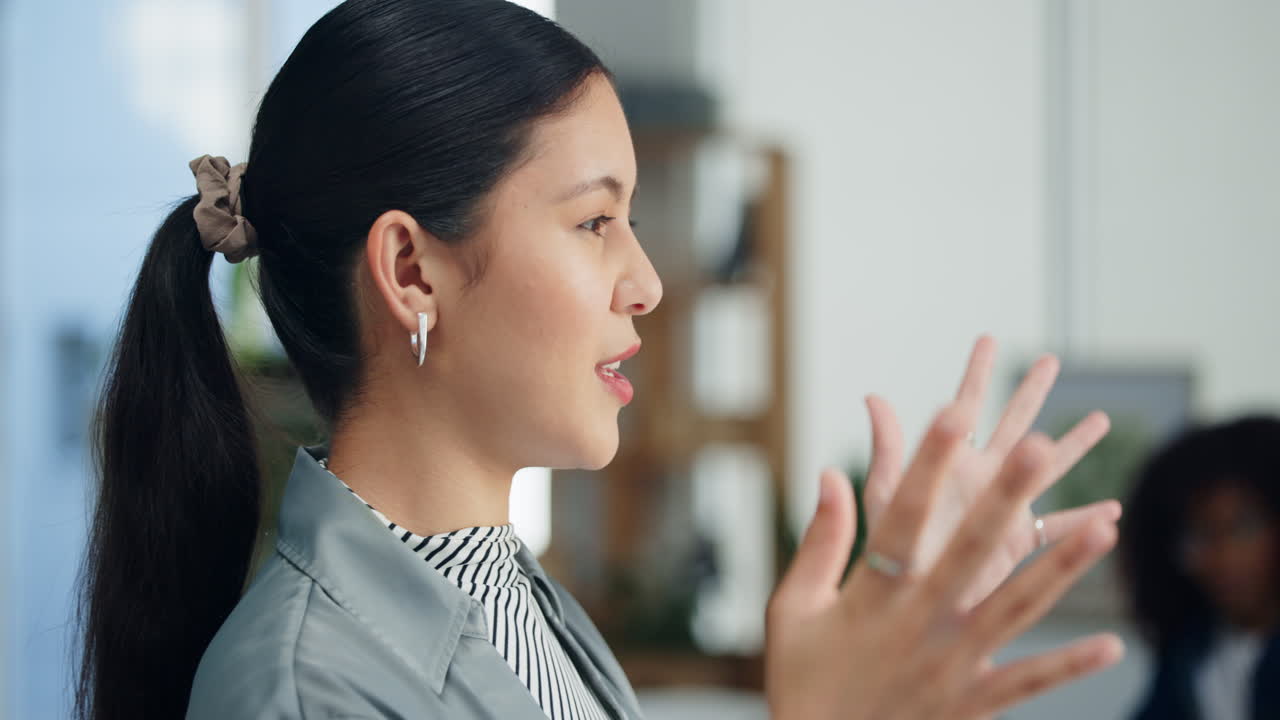 オフィスで話しながらジェスチャーをする若いアジア人女性