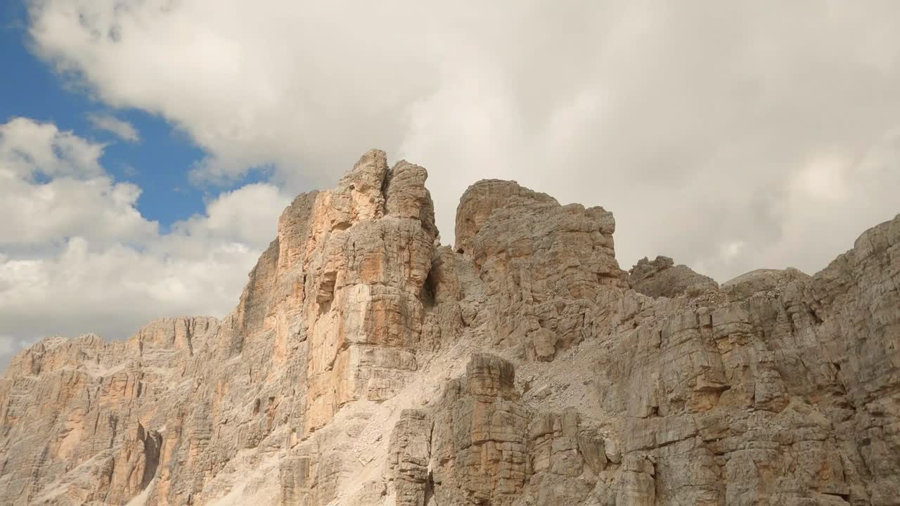Drone che sale sul Monte Lagazuoi, Dolomiti italiane, sfiorando la cresta rocciosa tra le nuvole