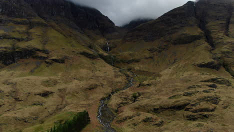 toma aérea cinematográfica de una pequeña cascada ubicada en el valle de las tierras altas de glencoe