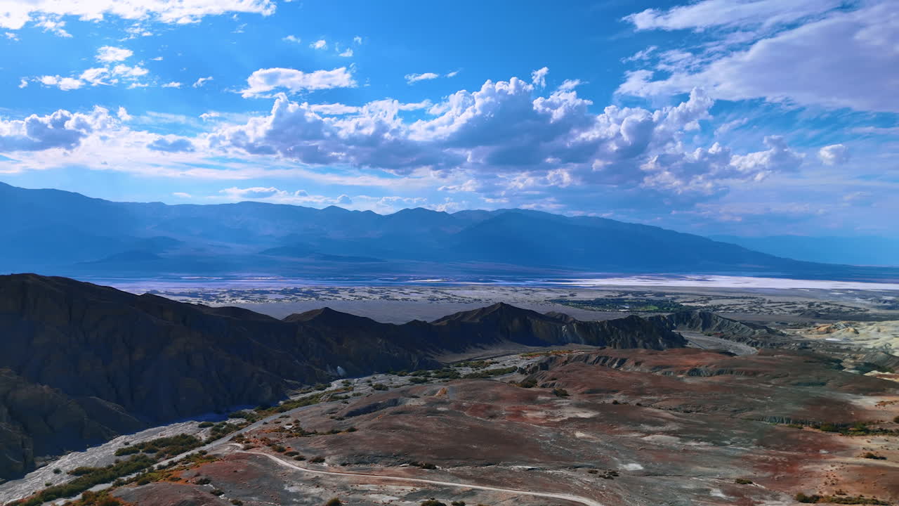 Breath-taking scenery of the vast desert dazzled by the hot sun. White fluffy cloudscape in the blue sky above. Aerial view on the Death Valley National Park, California, USA