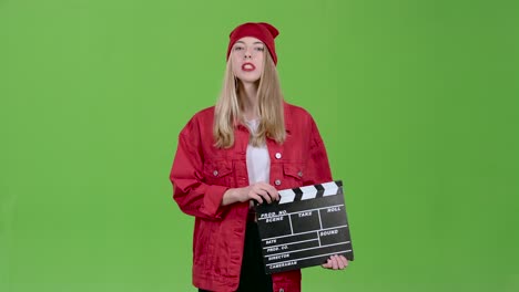 woman holding clapperboard in front of green screen