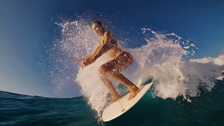 Dynamic video still of a surfer riding a wave, captured from a low-angle, showcasing the thrill