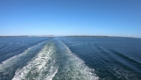 Distant-view-of-Seattle-city-coastline-panorama,-leaving-town-in-boat