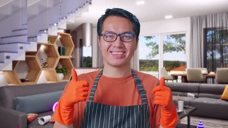 primer plano de una ama de casa asiática con un delantal sonriendo y mostrando los pulgares hacia arriba mientras está de pie en la casa