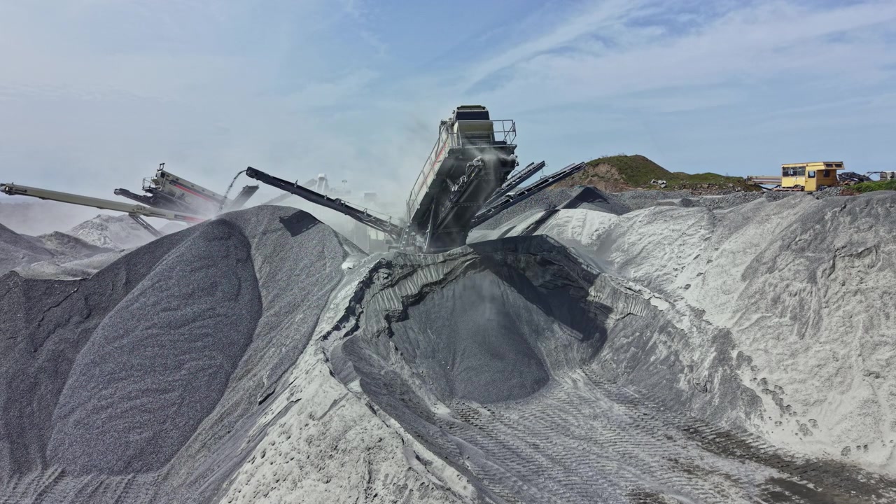 Granite quarry site with heavy machinery extracting stone and transporting materials to site for production during daytime