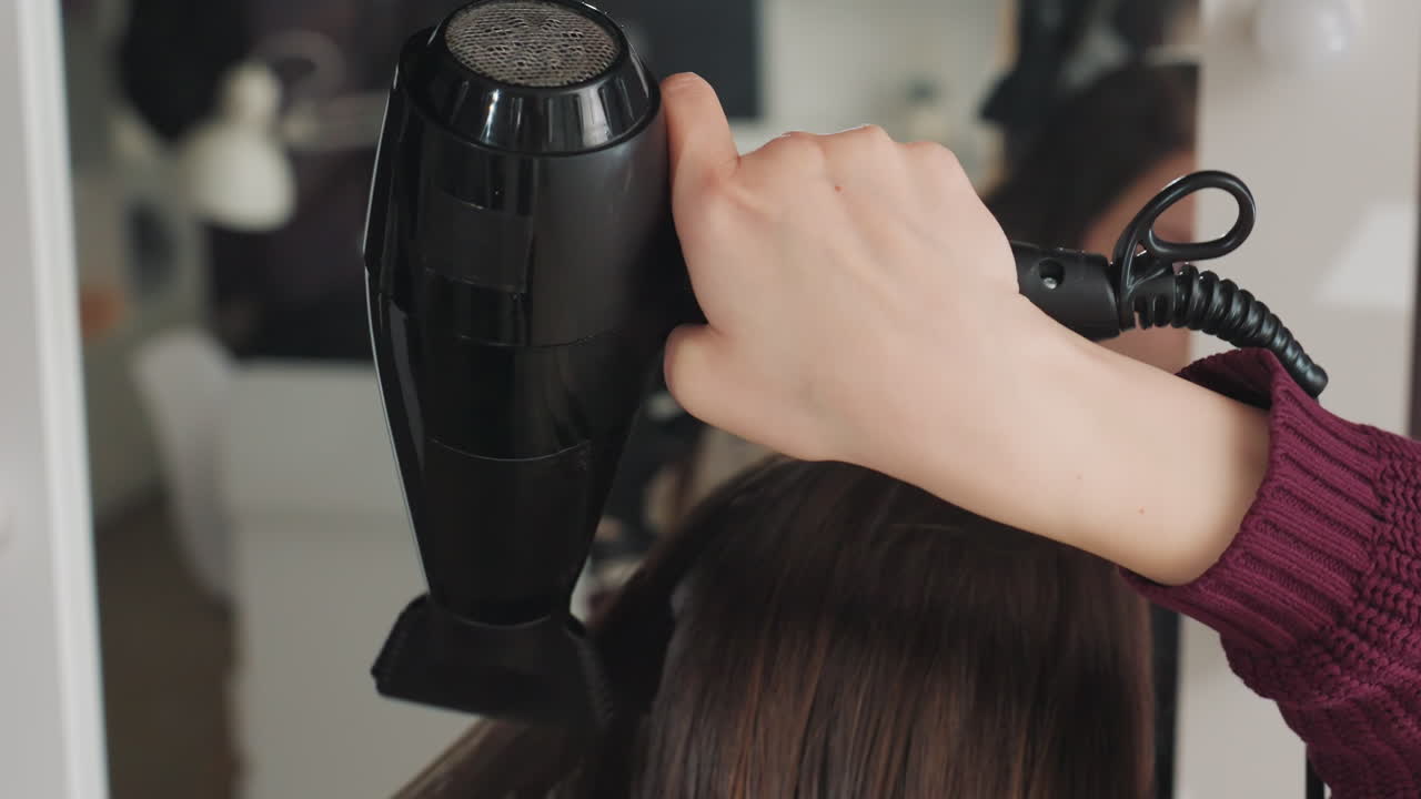 Primer plano de un estilista usando un secador de pelo, centrándose en las técnicas de peinado con control del calor y del flujo de aire, vista detallada de un profesional de la peluquería que gestiona el secado del cabello con precisión y habilidad