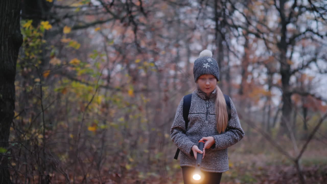 una niña camina por un bosque oscuro con una linterna en la mano se pierde en el concepto del bosque