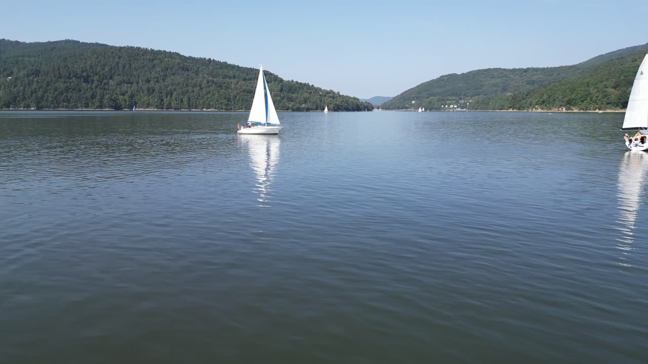 barcos en un lago tranquilo en las montañas beskid, navegando rodeados de vegetación durante un día de verano - vista aérea de avión no tripulado 4k