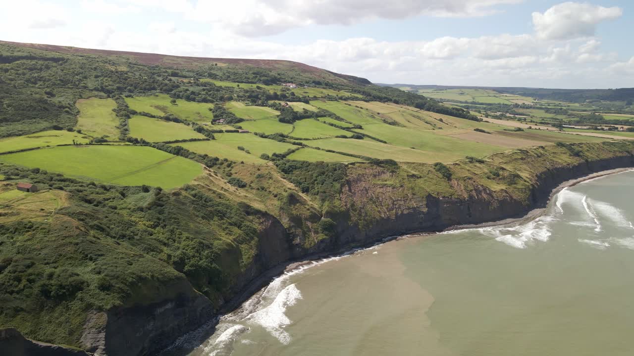 tomada aérea de drones de la costa de north yorkshire cerca de ravenscar con campos verdes y océano