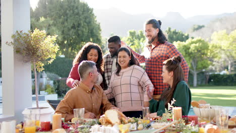 happy diverse male and female friends posing on thanksgiving celebration meal in sunny garden