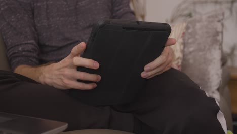 male relaxing and sitting on the sofa using a tablet device in landscape mode