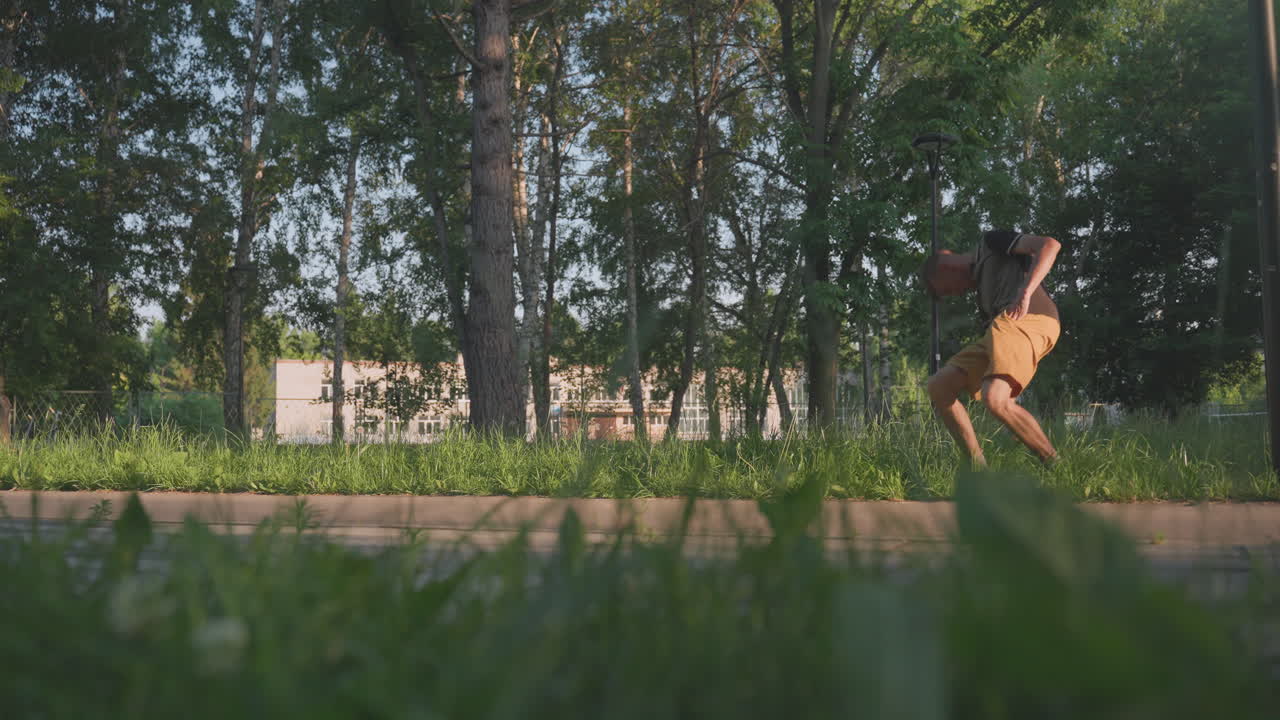 Young Man Walking Along TreeLined Park Path, LowAngle Grass Foreground And Birch Trunks In Background, Steady Stride And Summer Attire Visible, Warm Evening Light And Open Space Framing Movement
