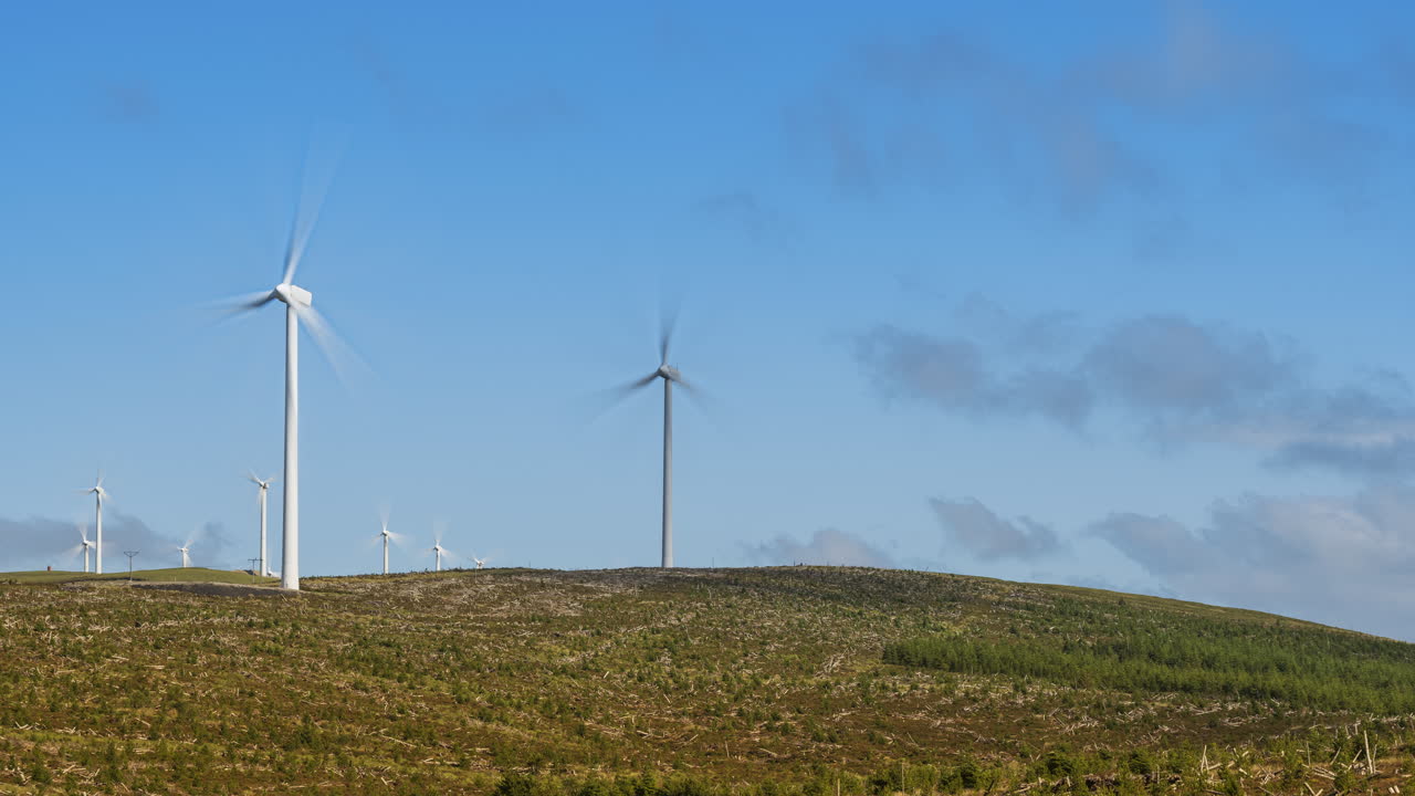 아일랜드에서 구름이 지나가는 낮 동안 외딴 풍경 지역에서 풍력 터빈의 시간 경과