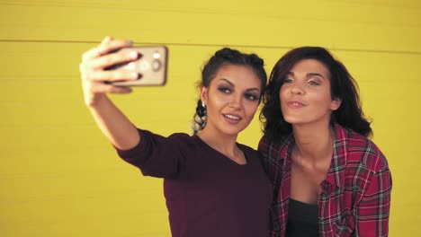 dos mujeres atractivas posando mientras toman selfie y muestran el signo de la paz
