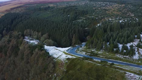 Vista-Aérea-De-Un-Automóvil-Conduciendo-A-Través-De-Un-Bosque-Cubierto-De-Nieve-En-Las-Montañas-De-Wicklow,-Con-Gente-Disfrutando-Del-Fondo-Del-Bosque-Nevado