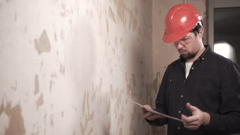 construction worker inspecting damaged wall