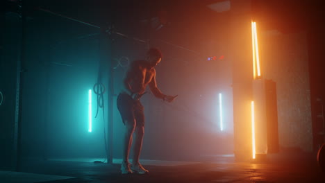 man jumping rope in the gym slow motion. bodybuilding man jumping hard on the rope in a dark and modern cross