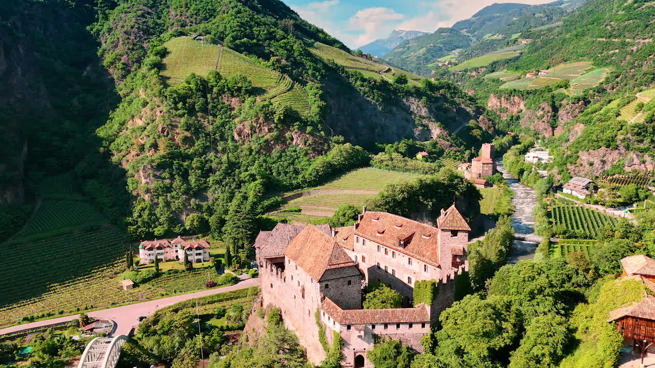 Flight around the beautiful medieval castle Runkelstein in Bolzano, South Tyrol, Italy. Amazing rocky landscape with vineyards growing on the slopes. Aerial view.