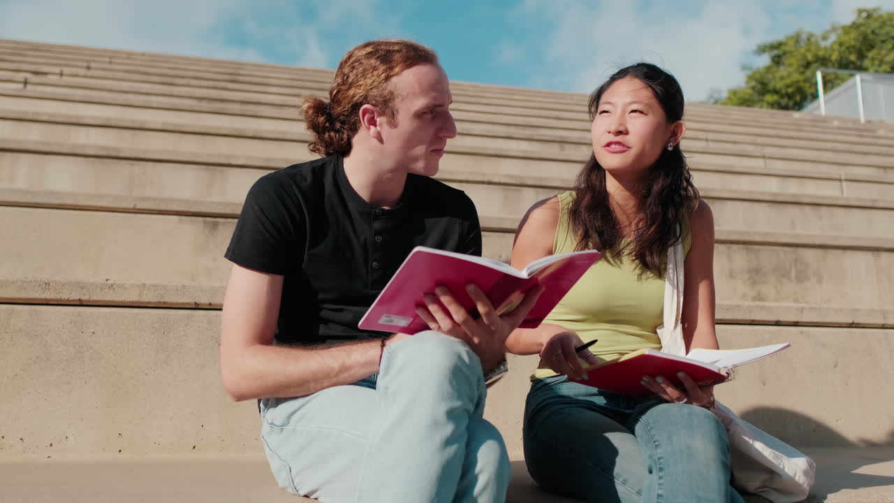 Side view of a girl and a boy, two students having fun talking outdoors