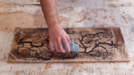 pouring epoxy resin on big wooden board with holes