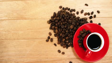 primer plano de una taza de café con platillo y granos de café