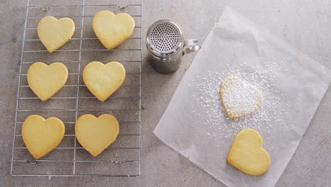 raw heart shape cookies on baking tray with flour shaker strainer and wax paper 4k